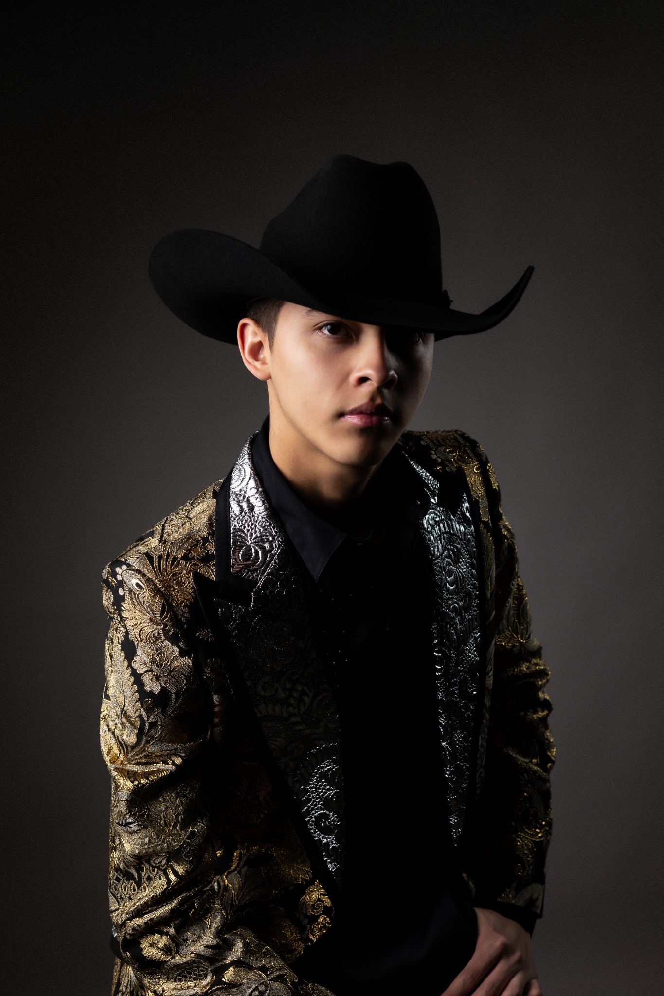 W Martínez con sombrero negro y saco dorado